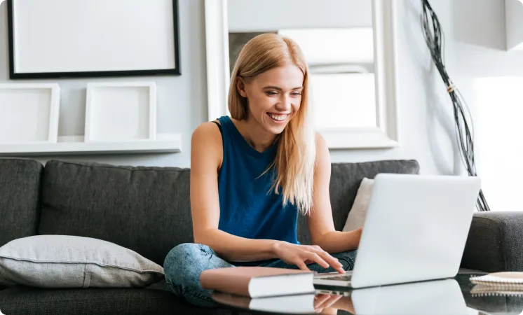 A student sitting on a sofa at home, working on a laptop